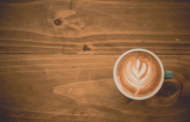 Arte calda Latte Coffee in una tazza sul tavolo in legno e luce del mattino