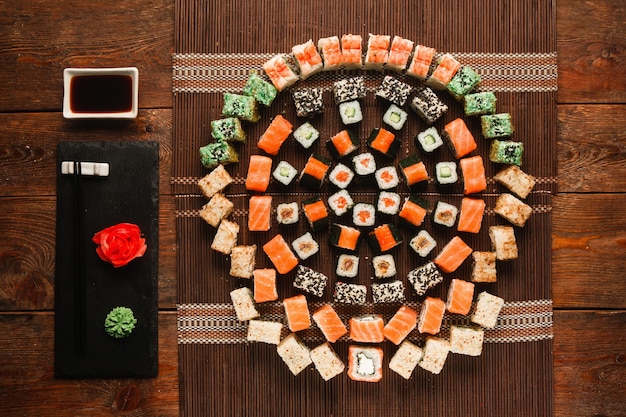 Arte del cibo, ottimo set di sushi. Appetitoso assortimento di panini, ornamento rotondo colorato servito su una stuoia di paglia marrone, piatto. Foto del menu del ristorante giapponese di lusso.