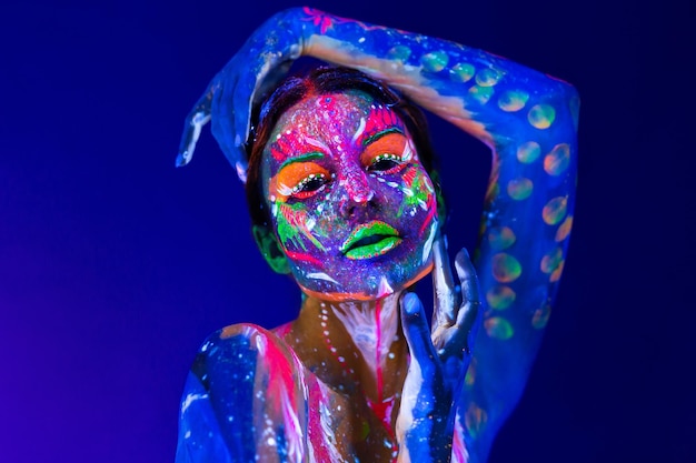 Arte del corpo incandescente alla luce ultravioletta. Body art sul corpo e sulla mano di una ragazza che brilla alla luce ultravioletta