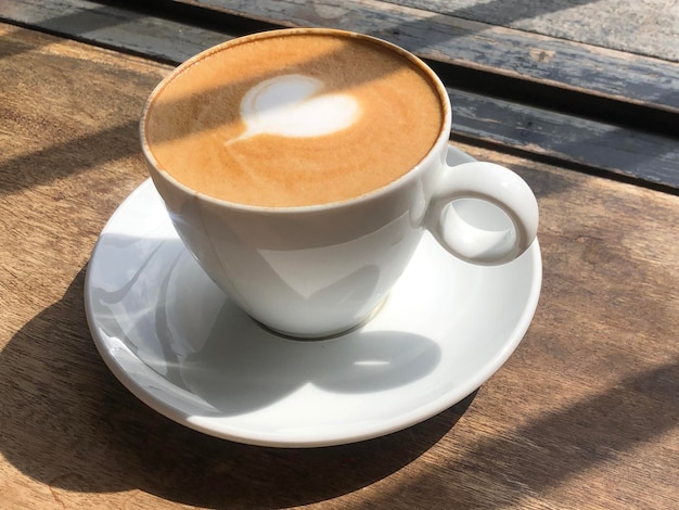 Arte del latte del cuore sulla tazza di caffè sul tavolo