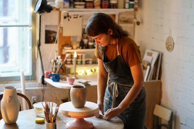 Arte per hobby o per piccole imprese lavora in uno studio di ceramica su un vaso di vasaio per un negozio di ceramiche fatte a mano