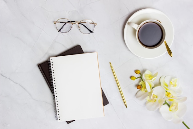 Articoli di lavoro con bicchieri di caffè, quaderni e penna sullo sfondo di marmo