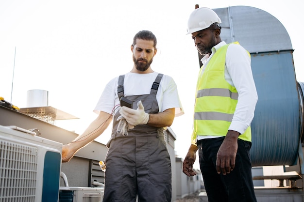 Artigiani che lavorano e mantengono i condizionatori sull'impianto