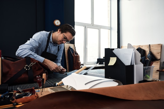 Artigiani della pelle che lavorano facendo meaupenets in modelli a tavola in studio di officina.