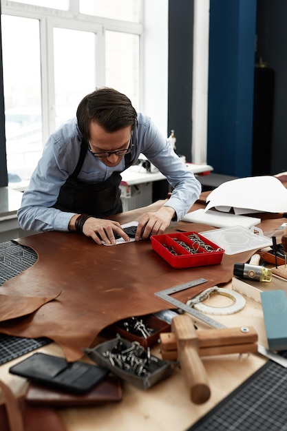 Artigiani della pelle che lavorano facendo meaupenets in modelli a tavola in studio di officina.