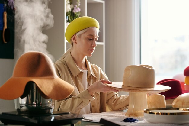 Artigiano femminile creativo seduto sul posto di lavoro nel negozio di artigianato