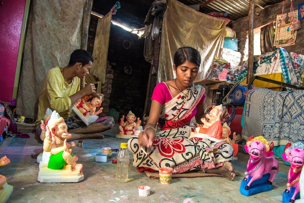 Artista che fa una statua e dà il tocco finale a un idolo del dio indù Lord Ganesha in un laboratorio di artisti per il festival di Ganesha