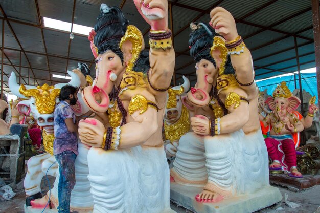 Artista che fa una statua e dà il tocco finale a un idolo del dio indù Lord Ganesha in un laboratorio di artisti per il festival di Ganesha