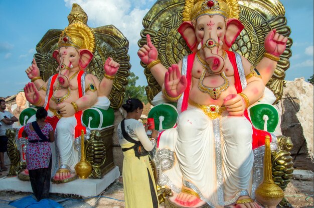 Artista che fa una statua e dà il tocco finale a un idolo del dio indù Lord Ganesha in un laboratorio di artisti per il festival di Ganesha