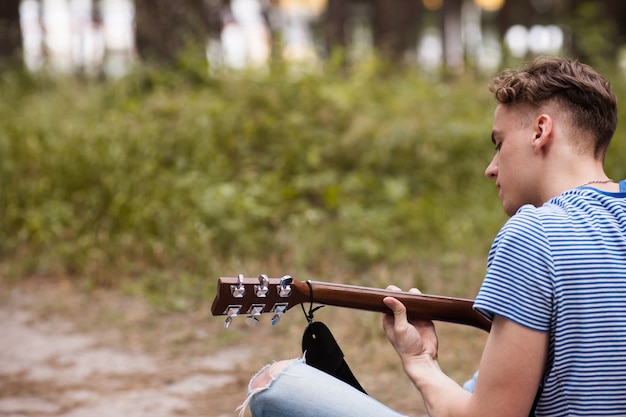 artista che suona la chitarra nella foresta. Bard escursionismo e stile di vita del viaggiatore