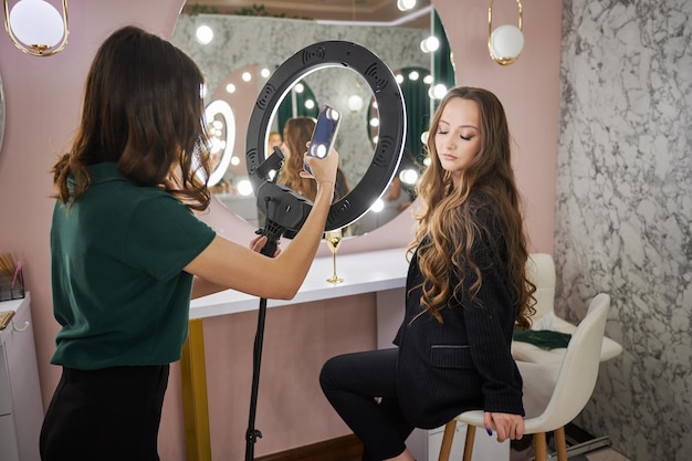 Artista del trucco che fotografa una donna in un salone di bellezza