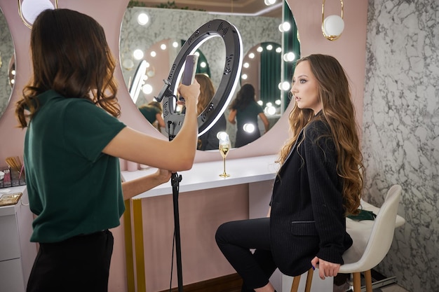 Artista del trucco che fotografa una donna in un salone di bellezza