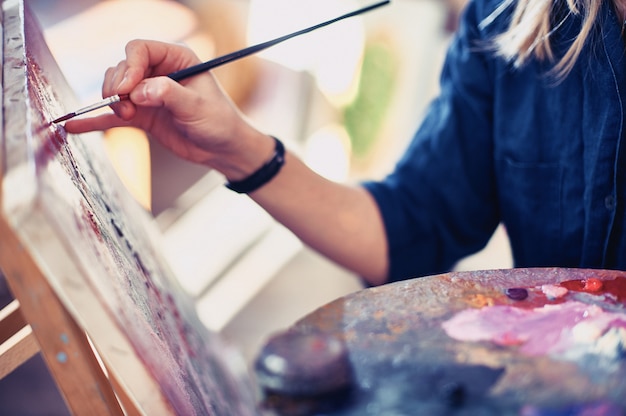 Artista della giovane donna che lavora alla pittura nello studio.