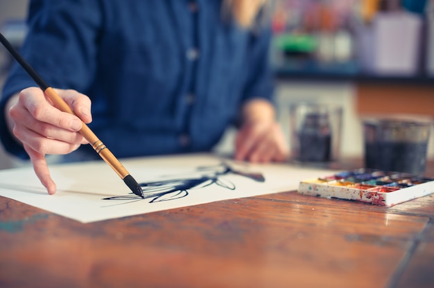 Artista della giovane donna che lavora alla pittura nello studio.