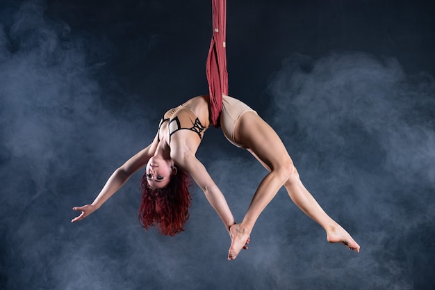 Artista di circo aereo flessibile sexy atletico femminile che balla sulla seta