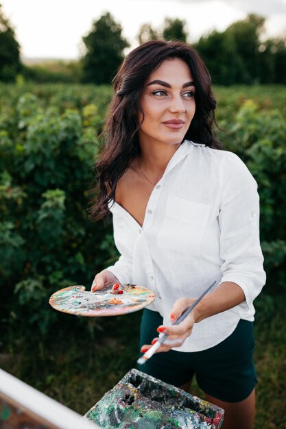 Artista di giovane bella donna con tavolozza da cavalletto e immagine di pittura pennello e sognare qualcosa di isolato