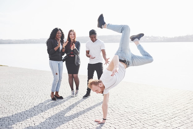 Artista di strada che breakdance all'aperto. Gli amici sorpresi applaudono