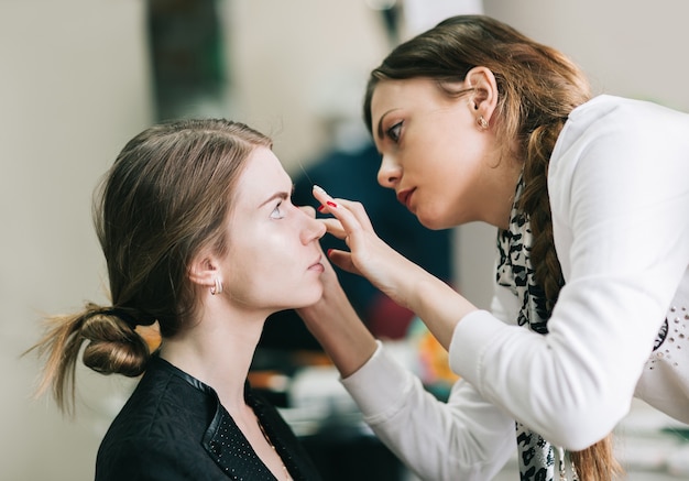 Artista di trucco che prepara sposa prima del matrimonio in una mattina