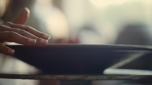 Artista donna sconosciuta che gira la ruota dei ceramisti in studio Ceramista non riconosciuto che tocca la pentola di argilla nel laboratorio Closeup mani di donna che torce il piatto in ceramica al rallentatore