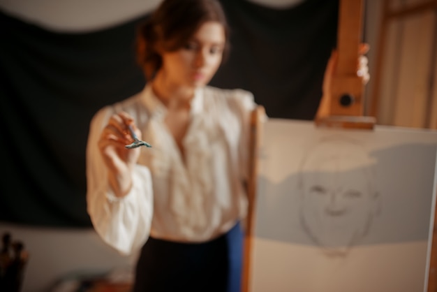 Artista femminile in piedi contro il cavalletto in studio