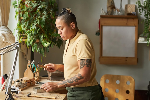 Artista femminile tatuata che crea gioielli fatti a mano