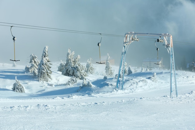 Ascensore di superficie (T-bar) e abeti innevati ghiacciati sulla collina di mattina d'inverno.