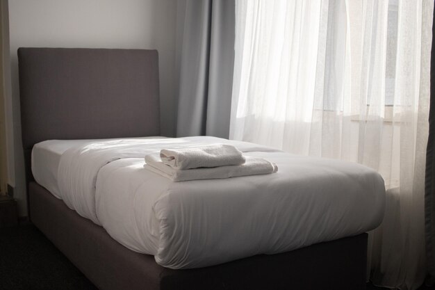 Asciugamani puliti bianchi impilati sul letto dell'hotel. Foto di alta qualità