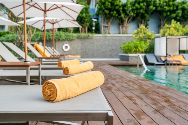 Asciugamano arroto arancio su uno sfondo di sdraio in piscina nel resort o hotel.