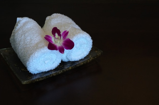 Asciugamano bianco e fiori di orchidea in un bagno dell'hotel