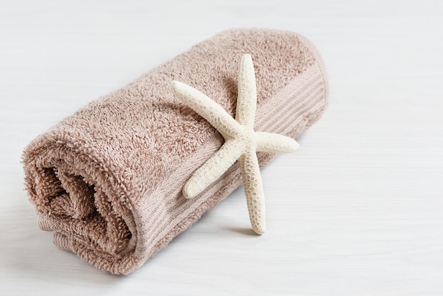 Asciugamano con stelle marine su tavola di legno bianca Asciugamano da bagno soffice marrone