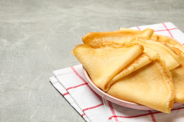 Asciugamano da cucina con piatto di frittelle sottili sul tavolo grigio