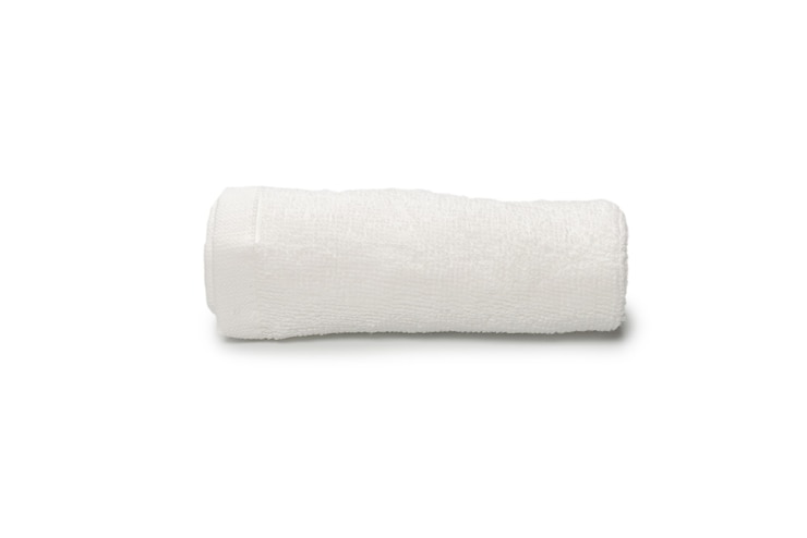 Foto asciugamano di cotone soffice bianco isolato su uno sfondo bianco. spa e resort.