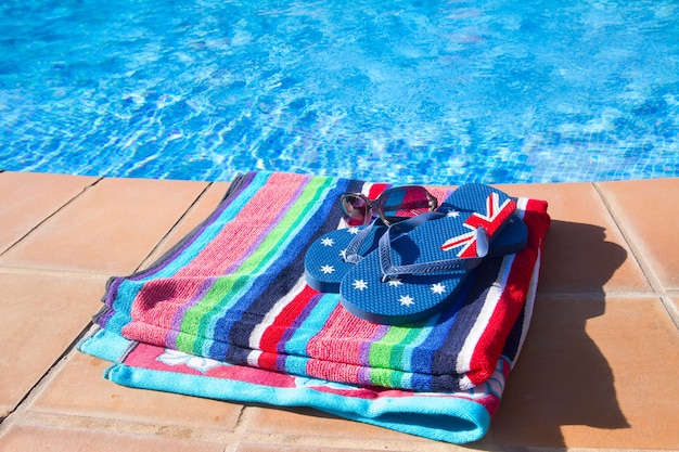 Asciugamano e sandalo vicino all'acqua blu della piscina