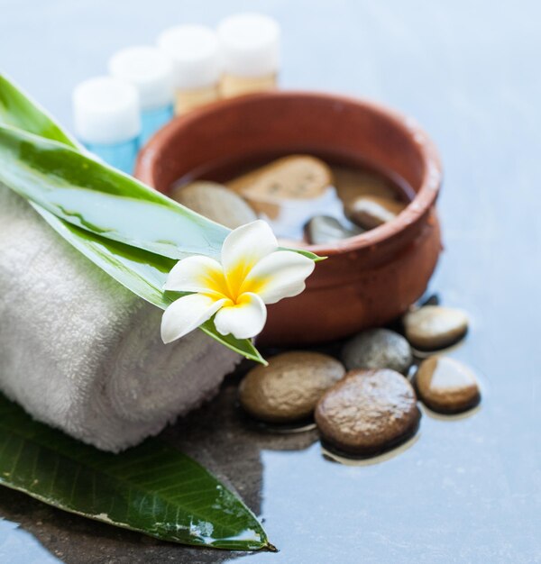 Asciugamano fiori tropicali foglie verdi e cosmetici su sfondo di marmo scuro