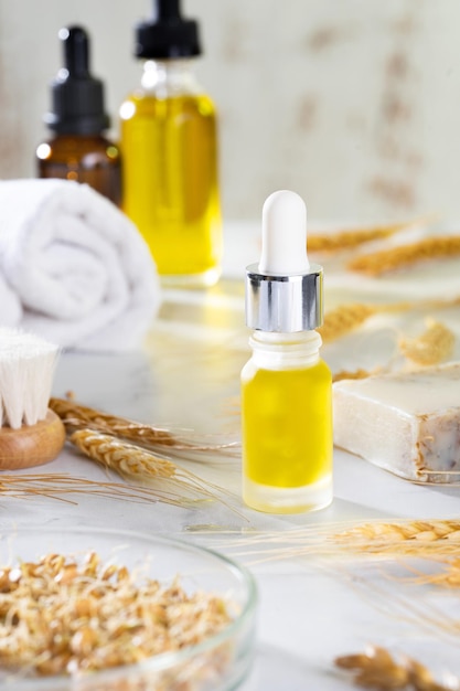 Asciugamano per spazzole da bagno oli e germogli di grano sul tavolo cosmetico in bagno Un set di cosmetici biologici in fiale di vetro con contagocce per la cura della pelle e dei capelli Il concetto di cura di sé e spa