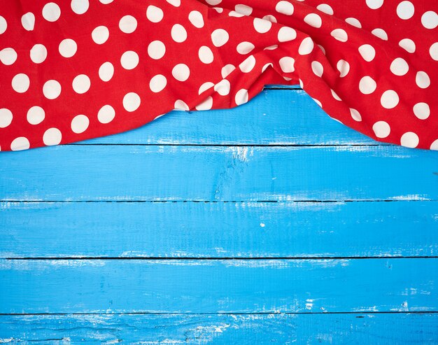 Asciugamano rosso del tessuto con i cerchi bianchi su un fondo di legno blu