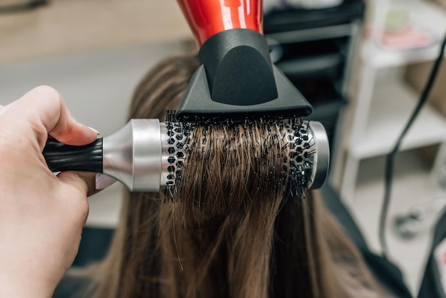 Asciugare i capelli biondi con un asciugacapelli e una spazzola rotonda