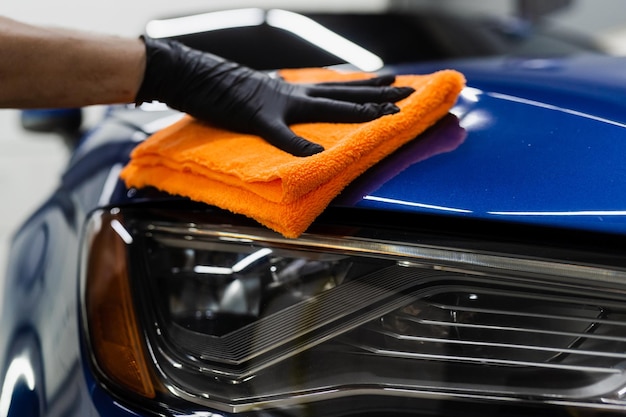 Asciugatura manuale dell'auto con microfibra nei dettagli del servizio automatico Auto addetto alle pulizie con carrozzeria asciutta dopo il lavaggio dell'automobile