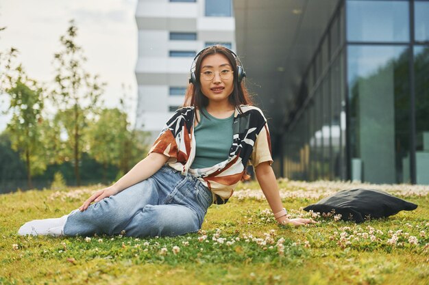 Ascolta la musica in cuffia La giovane donna asiatica è all'aperto durante il giorno