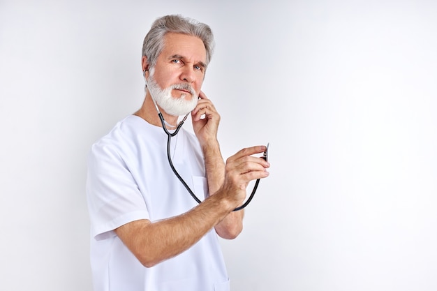 Ascoltiamo il tuo battito cardiaco, vecchio medico esperto usa lo stetoscopio al lavoro, pronto ad aiutare