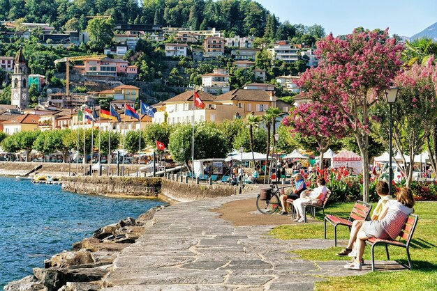 Ascona, Svizzera - 23 agosto 2016: Turisti seduti sulla panchina presso l'argine di Ascona lussuoso resort sul Lago Maggiore, Canton Ticino, Svizzera.