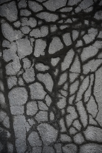 asfalto nella trama di crepe / crepe di sfondo astratto su strada asfaltata