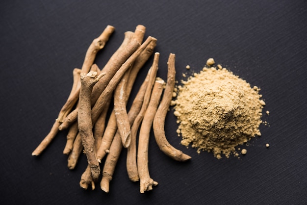 Ashwagandha o Aswaganda O Indian Ginseng è una medicina ayurvedica sotto forma di gambo e polvere. Isolato su sfondo semplice. messa a fuoco selettiva