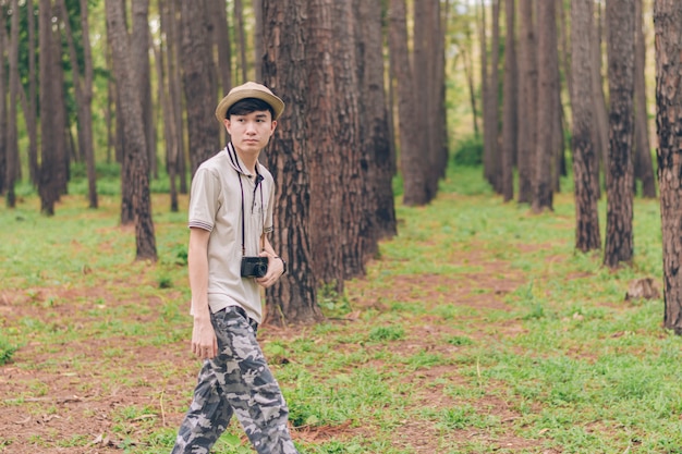 Asia uomo indossa camicia, cappello e pantaloni mimetici, cammina e scatta foto nella foresta