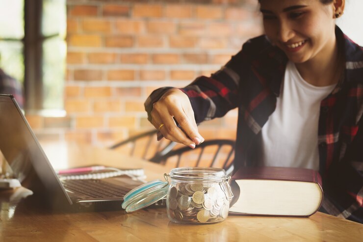 Photo asia woman putting money coins into the glass bottle for save money