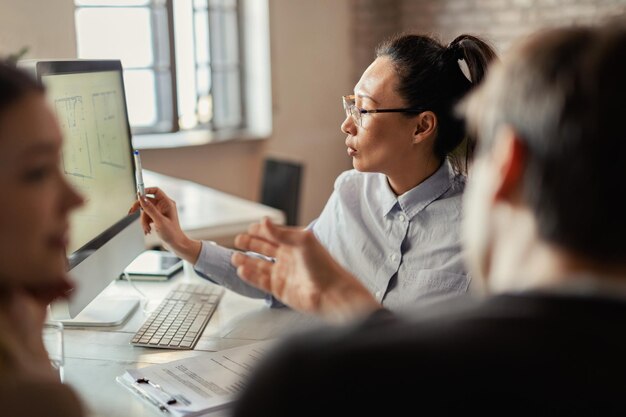 Asian insurance agent using computer while advising her clients during a meeting in the office
