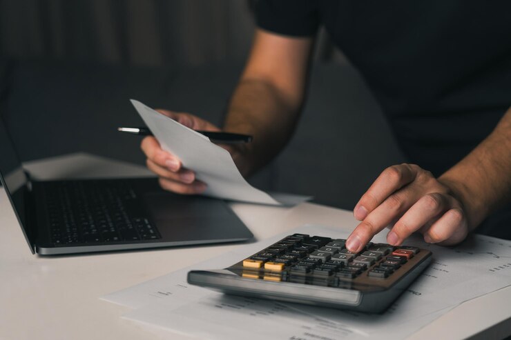 Asian man using calculator to calculate expenses while holding family bills at his home