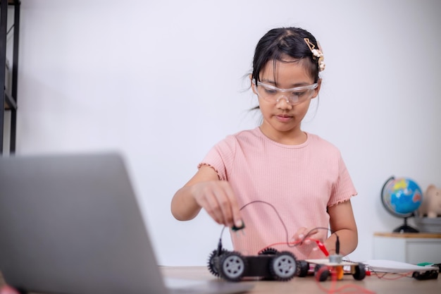 Asian students learn at home by coding robot cars and electronic board cables in STEM STEAM mathematics engineering science technology computer code in robotics for kids' concepts