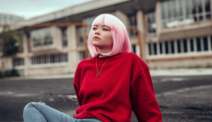 Foto asian teen girl che guarda lontano mentre è seduto a terra in città