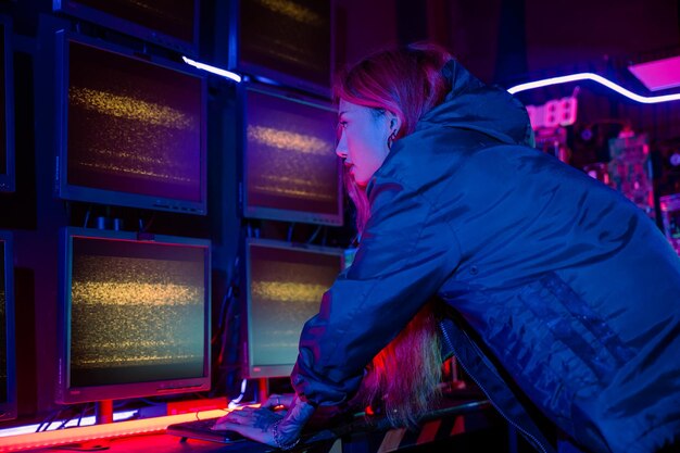 asian woman wearing a black jacket hacking programming system and working with computer monitor display in dark office cyber security agency developing website cyber security